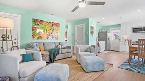Un salon moderne comprenant un ensemble de canapés, un pouf et une grande œuvre d’art à motifs floraux.