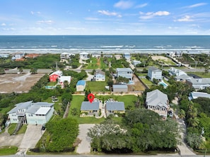 Vista aérea de una zona residencial costera con casas, una piscina y una playa al fondo.