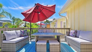 An outdoor patio with wicker furniture, a table, and a red umbrella.