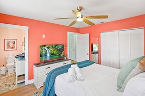 Un dormitorio con cama, televisión, ventilador de techo, armario y baño con inodoro y lavabo.
