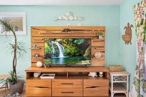 A wooden entertainment unit with a flat-screen TV displaying a waterfall scene, wooden drawers, and decorative items.