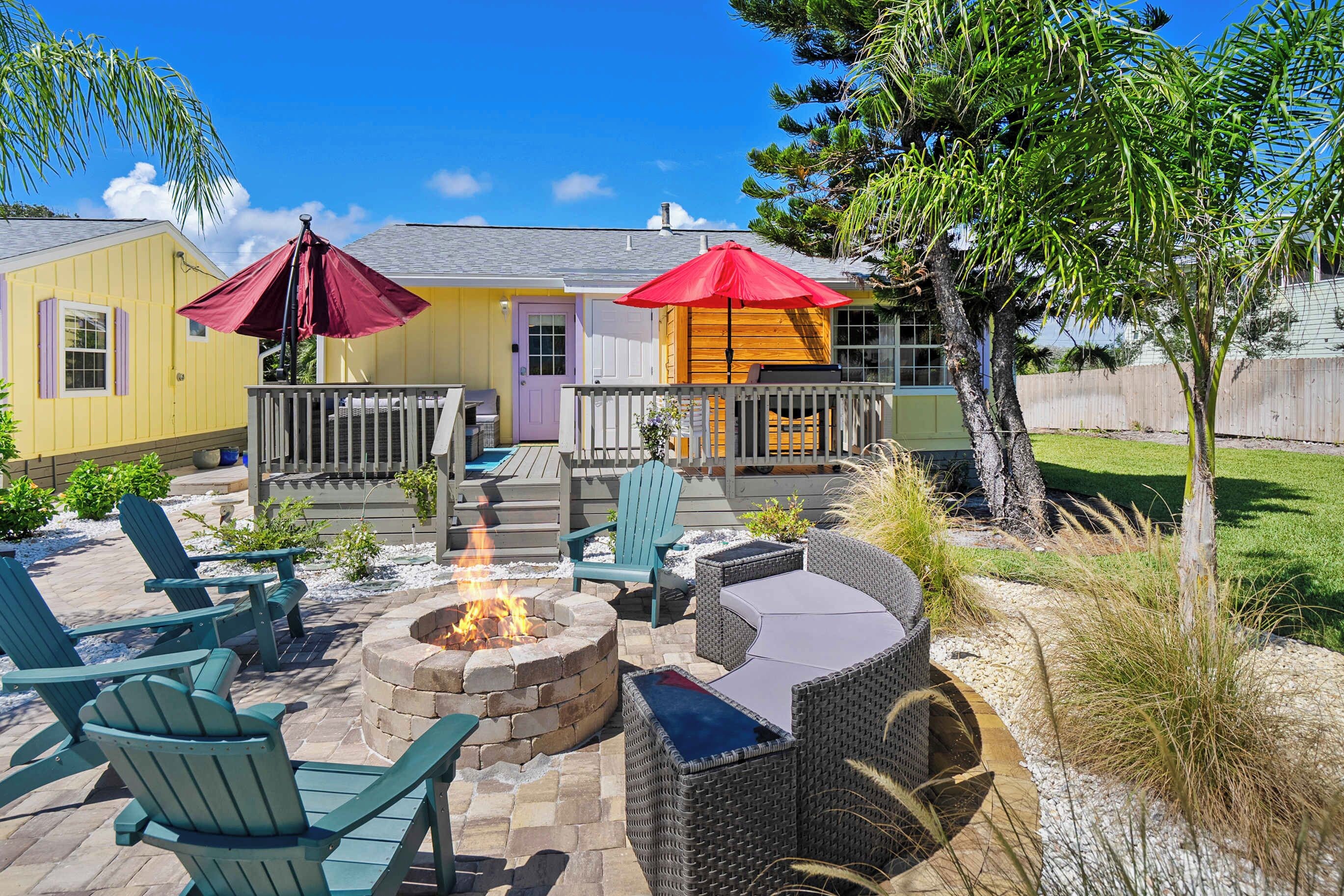 A patio area with outdoor furniture, a fire pit, and umbrellas.