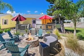 A patio area with outdoor furniture, a fire pit, and umbrellas.
