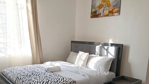 A neatly arranged bedroom with a bed, bedside tables, and a rug.