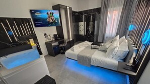 Una habitación de hotel moderna con cama, televisor, zona de ducha y lavamanos.