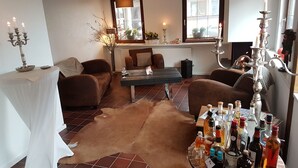 Una sala de estar acogedora con un sofá, una mesa de centro y una chimenea. Hay velas y varias botellas sobre la mesa.