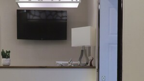 Un área de recepción moderna con un separador de diseño de piedra, un televisor de pantalla plana y una lámpara minimalista.
