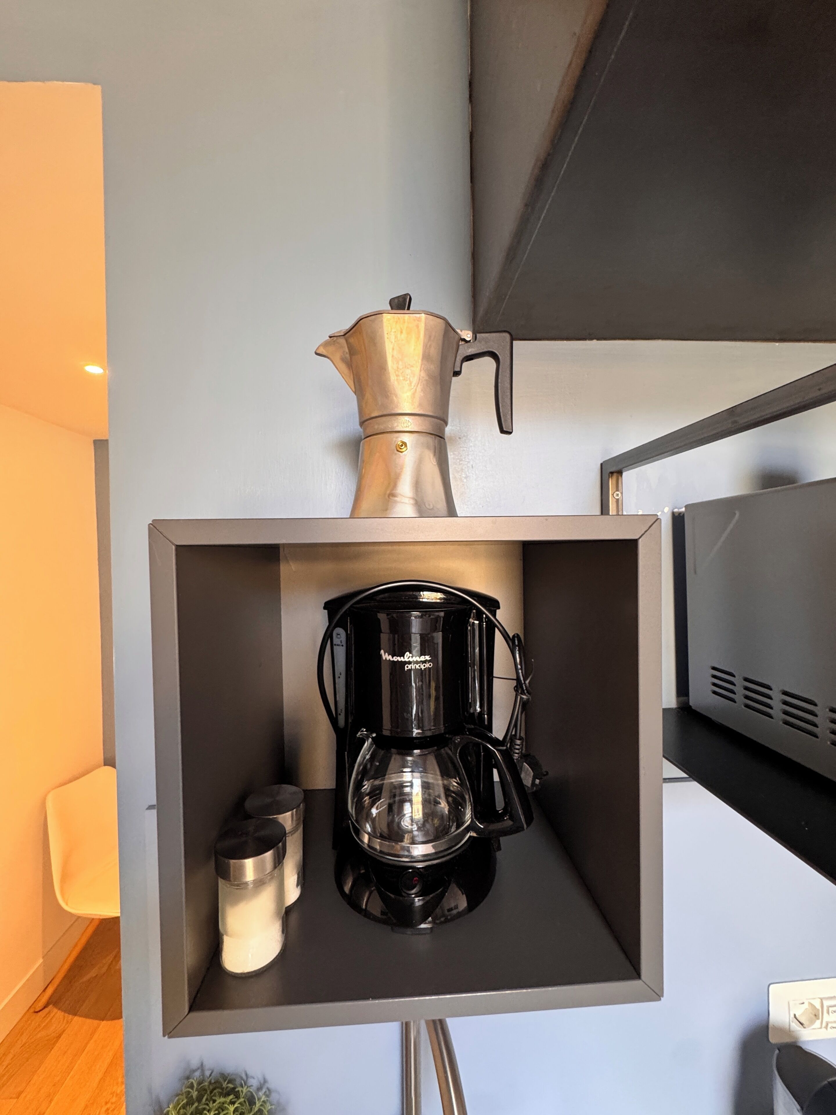 Una cocina moderna con cafetera y hervidor en un mueble empotrado.