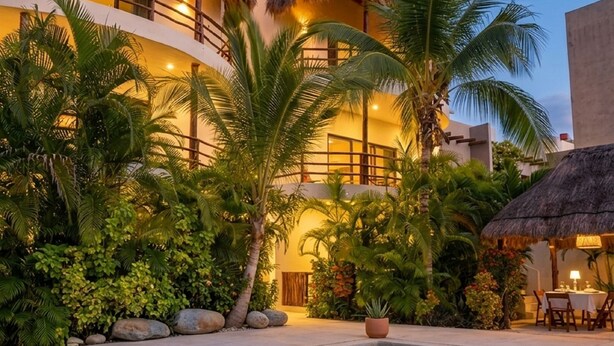 Een resort met een zwembad, palmbomen en een gebouw met rieten dak.