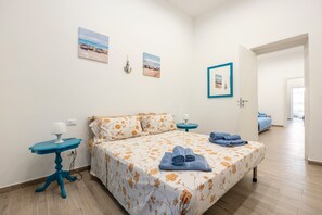 Une chambre à coucher avec un lit, une table de chevet, une lampe et un mur décoré de tableaux.