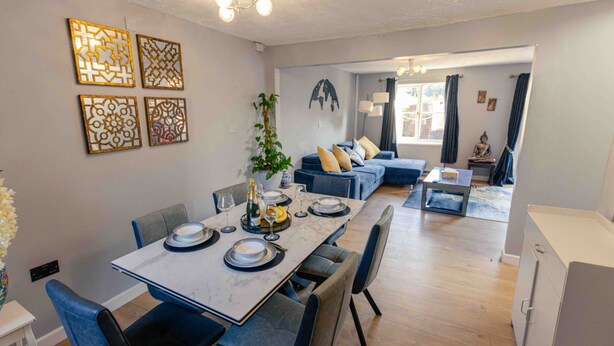 En matplats med ett bord dukat för fyra personer, en soffa och ett litet sidobord med en statyett.