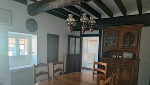 A dining room with a wooden table and chairs, a chandelier, and a wooden cabinet.