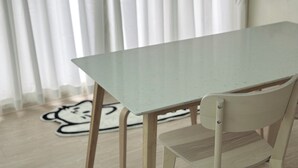 Ein Esstisch mit einem Stuhl, Holzboden und einem Teppich mit Comic-Motiv.