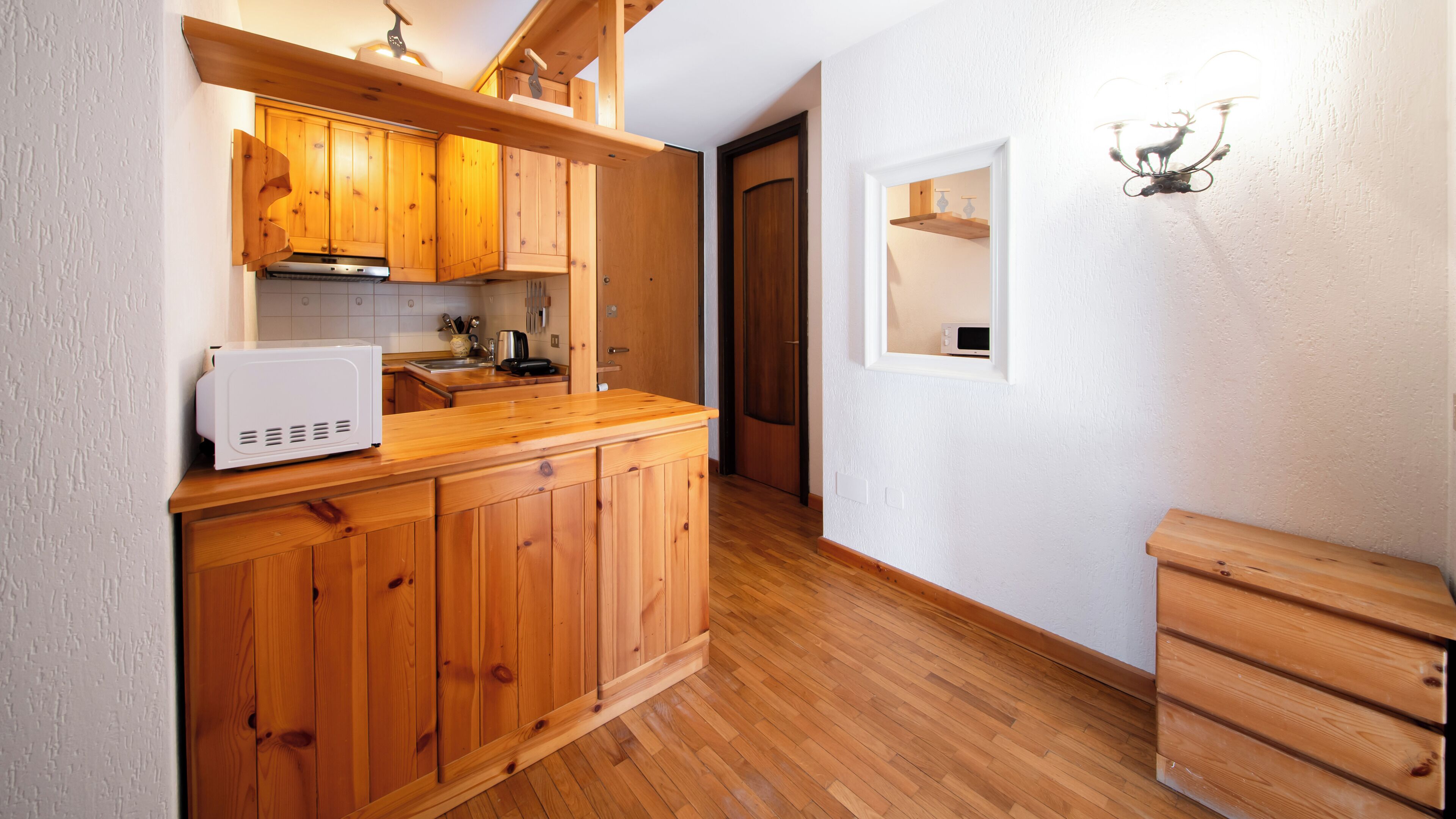 Une cuisine de taille réduite, dotée de meubles en bois, d’un four à micro-ondes et d’un évier.