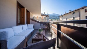 Un balcon avec un canapé blanc, des meubles en osier et une table sur laquelle est posé un panier rempli de fleurs.