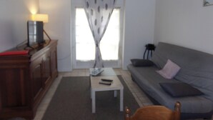 Ein Wohnzimmer mit einer Couch, einem Couchtisch, einer Lampe und einem Fenster mit Vorhängen.