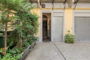 A narrow alleyway with a concrete path, a metal gate, and a small entrance to a building. - Giolitti San Carlo Stay by Wonderful Italy (Turin)