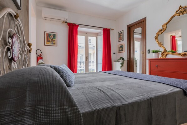 Une chambre à coucher comprenant un lit, une commode, un miroir et une porte donnant sur un balcon.