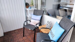 A balcony with two black wicker chairs, one with a blue cushion and the other with a multicolored cushion. - Cozy Apartment with Stunning Views in Marina Wendtorf (Wendtorf)