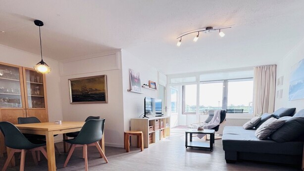 A modern living room with a dining area, a sofa, and a TV. - Cozy Apartment with Stunning Views in Marina Wendtorf (Wendtorf)