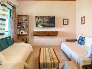 A room with two beds, a bookshelf, a painting, and a small table.