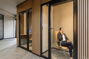 A modern office space with a glass partition, a wooden panel wall, and a single office chair.