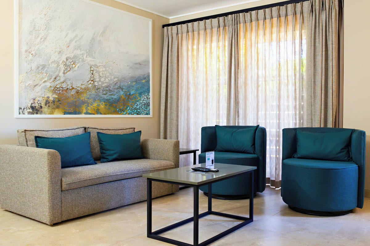 A living room with a sofa, two armchairs, a coffee table, and a large abstract painting on the wall.