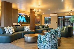 A modern hotel lobby with a curved sofa, round coffee table, and a large TV screen. - Menlyn Mix (Pretoria)
