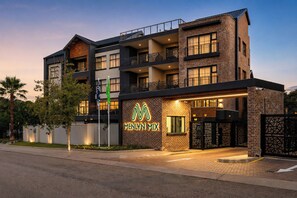 A multi-story hotel with a prominent 'Menlyn Mix' sign, balconies, and a brick facade.