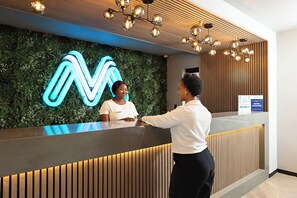 A reception desk with a neon sign, a wooden panel wall, and a ceiling light fixture.