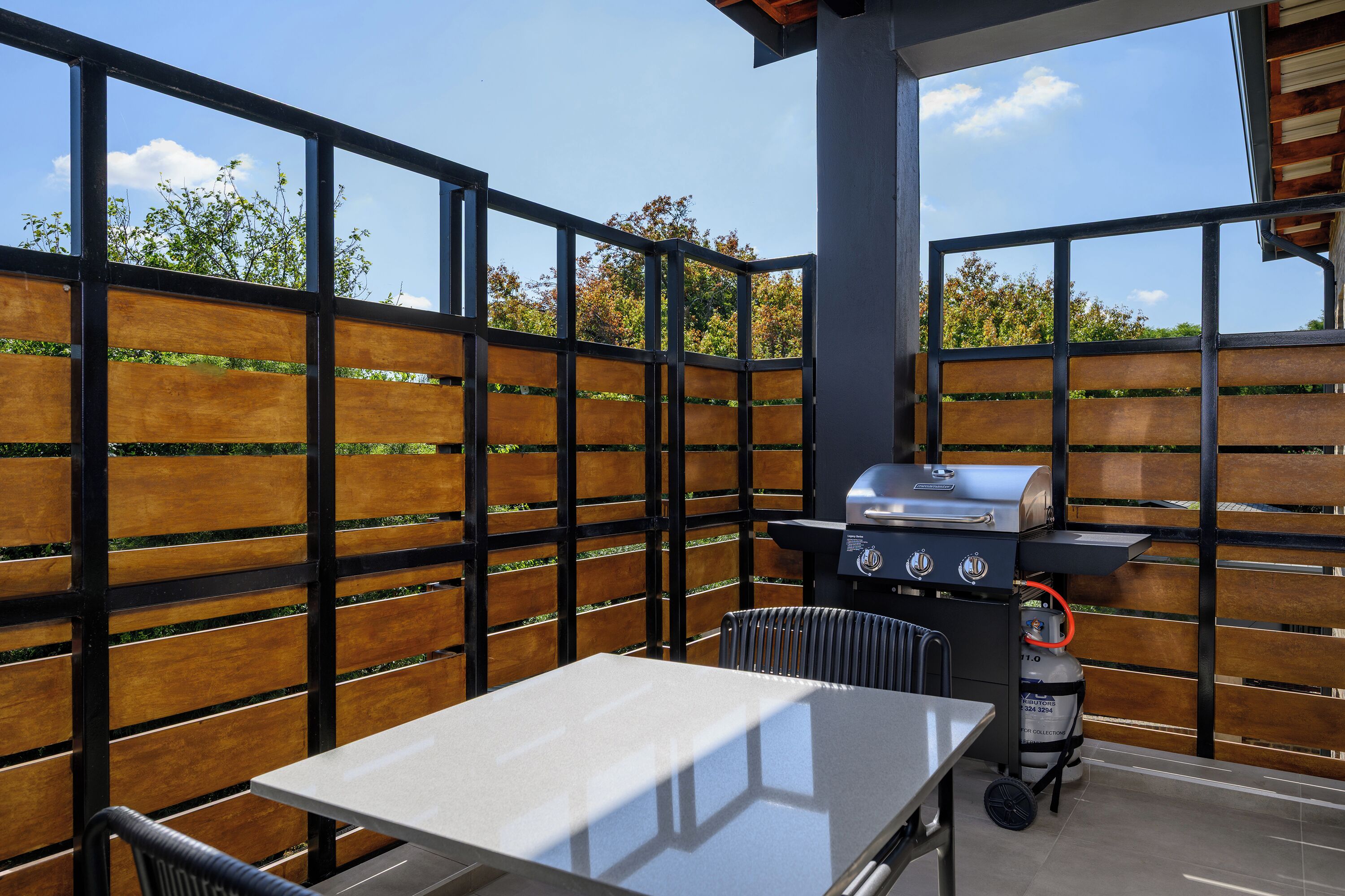 An outdoor patio with a grill, table, and chairs.