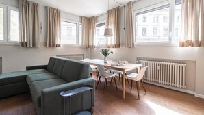 Uma sala de estar moderna com um sofá de canto, uma mesa de jantar com cadeiras e um radiador.