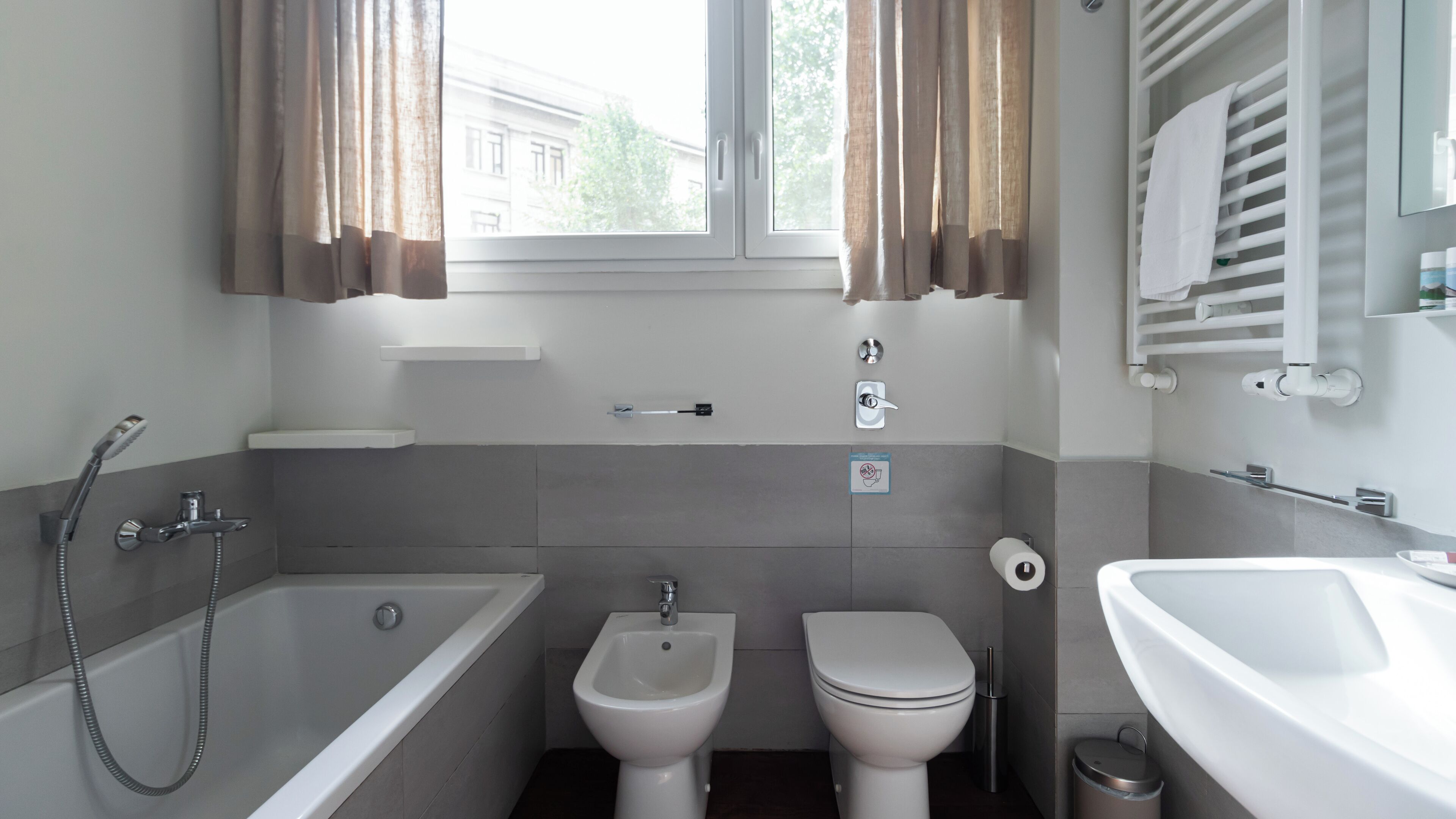 Een moderne badkamer met een bad, toilet, wastafel en bidet.