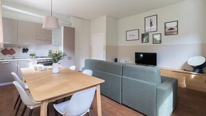 Um espaço de estar moderno com área de jantar, sofá, TV e cozinha.