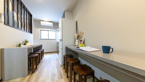 Une cuisine moderne avec des tabourets en bois, un réfrigérateur blanc et une fenêtre qui laisse entrer la lumière naturelle.