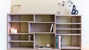 Une bibliothèque en bois, dotée de plusieurs étagères, dont certaines contiennent des livres et des objets décoratifs.