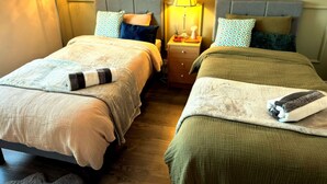 Two beds with headboards, bedside tables, lamps, patterned wall wallpaper, and a wooden floor. - Cosy Stay in Coventry CV5 | King Bed & Twin Room | Free Parking | Sleeps 4 (Coventry)