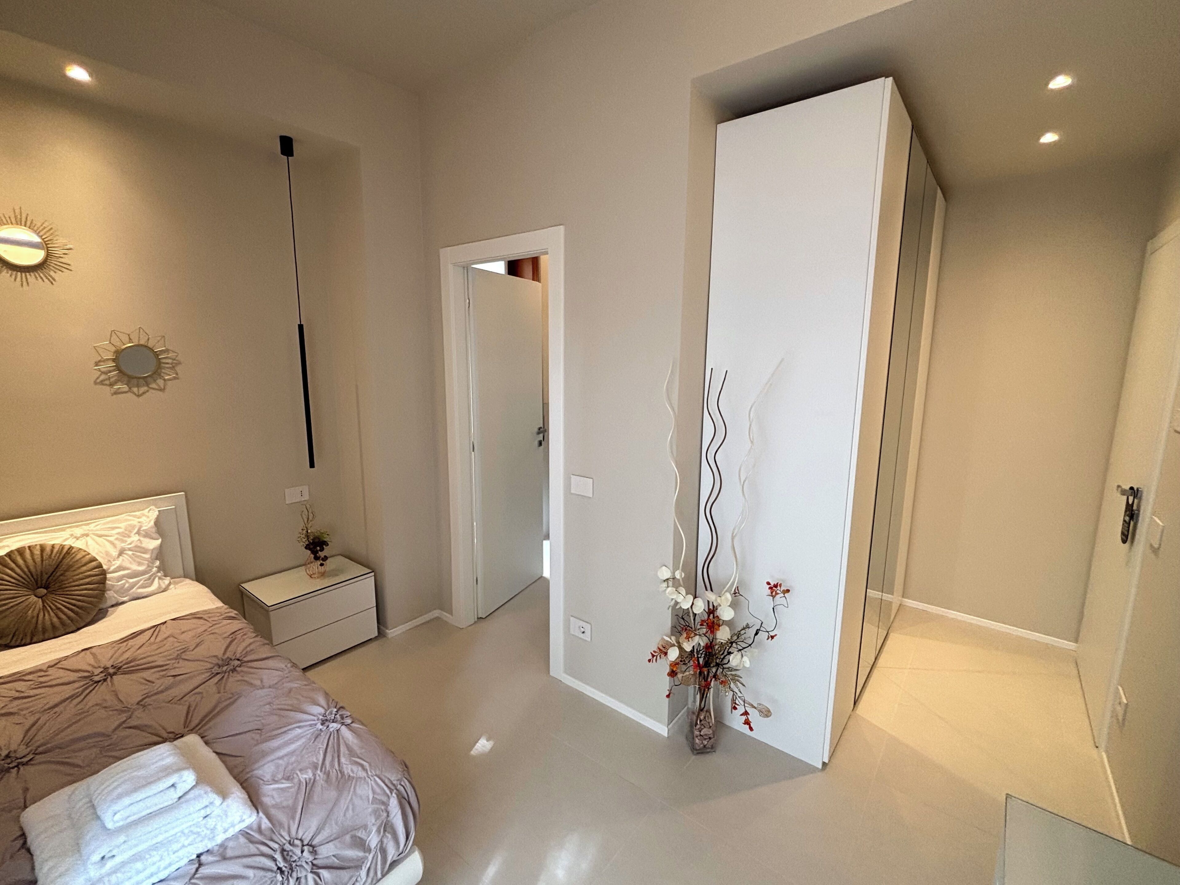 Un dormitorio moderno con cama, mesita de noche y armario.