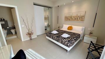 A modern bedroom with a zebra-striped bed, a small bedside table with a vase, and a large mirror on the wall.