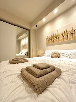Une chambre moderne avec un grand lit, un miroir et une œuvre d’art accrochée au mur.