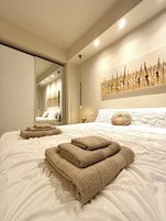 Un dormitorio moderno con una cama grande, un espejo y una obra de arte en la pared.