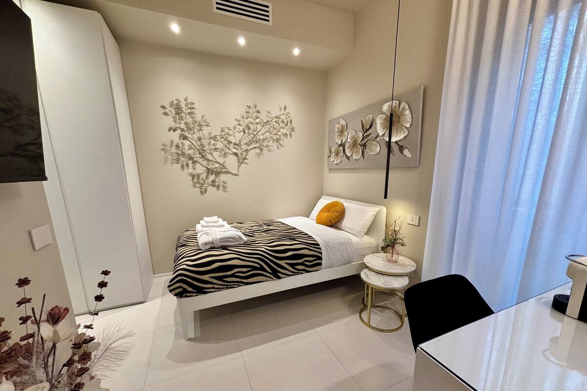Een moderne slaapkamer met een bed met zebraprint, een klein rond tafeltje en een kunstwerk aan de muur.