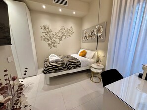 Une chambre moderne avec un lit à motifs zébrés, une petite table ronde et une œuvre d’art accrochée au mur.
