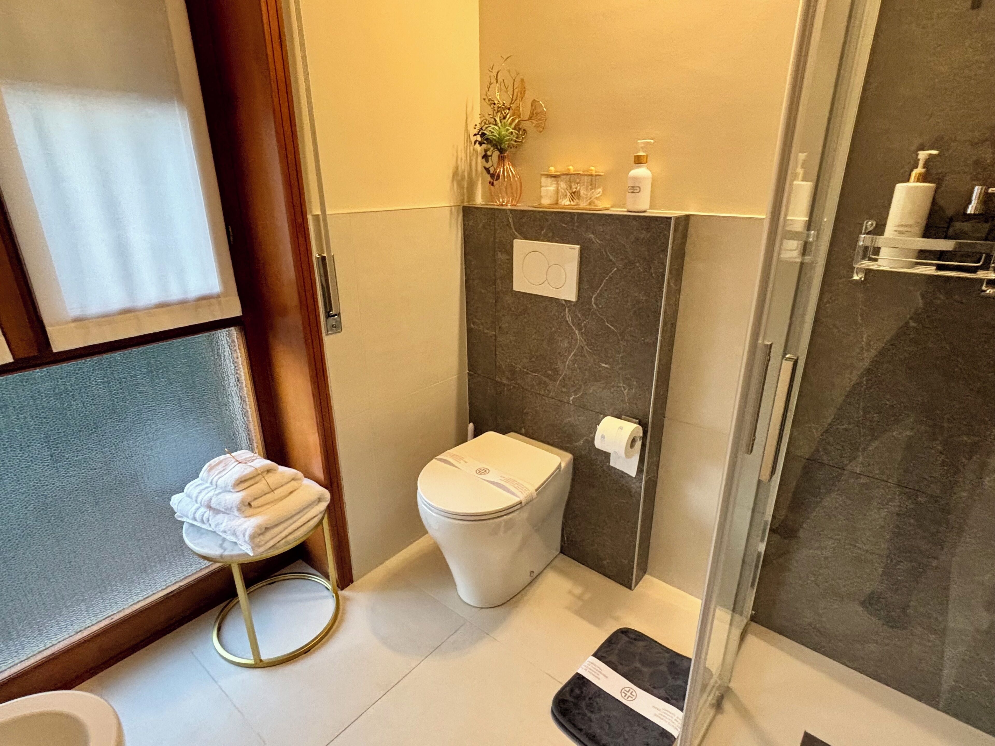 A modern bathroom with a toilet, a glass shower enclosure, and a towel rack.