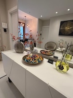 Una cocina moderna con encimera blanca, jarrones decorativos y un espejo grande.