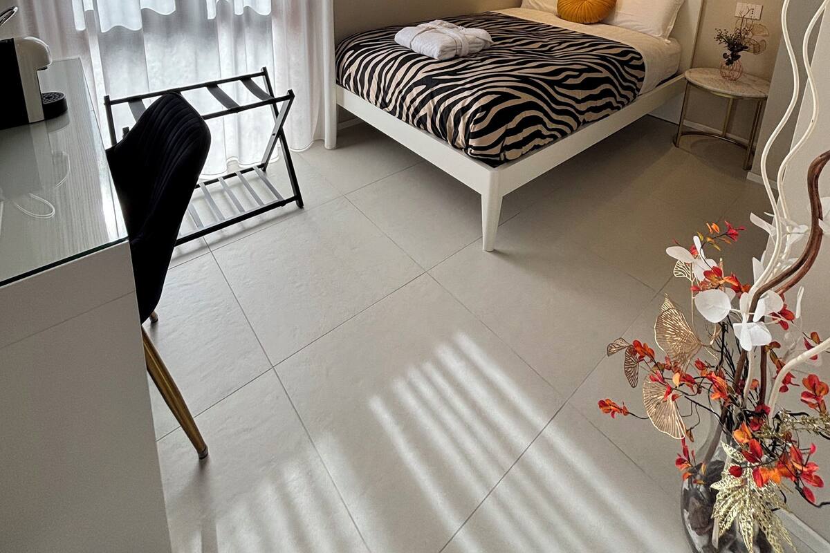 Een moderne slaapkamer met een bed met zebraprint, een grote spiegel en een decoratieve plant.