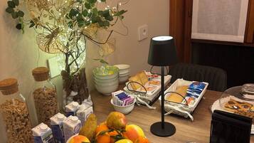 A breakfast buffet with various food items, a decorative plant, and breakfast essentials on a wooden table.