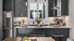 A modern kitchen with dark cabinets, stainless steel appliances, and a central island with seating.