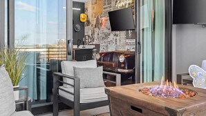 A modern living room with a glass partition, a leather sofa, a wooden coffee table with a fire feature, and a wall decorated with newspaper clippings.