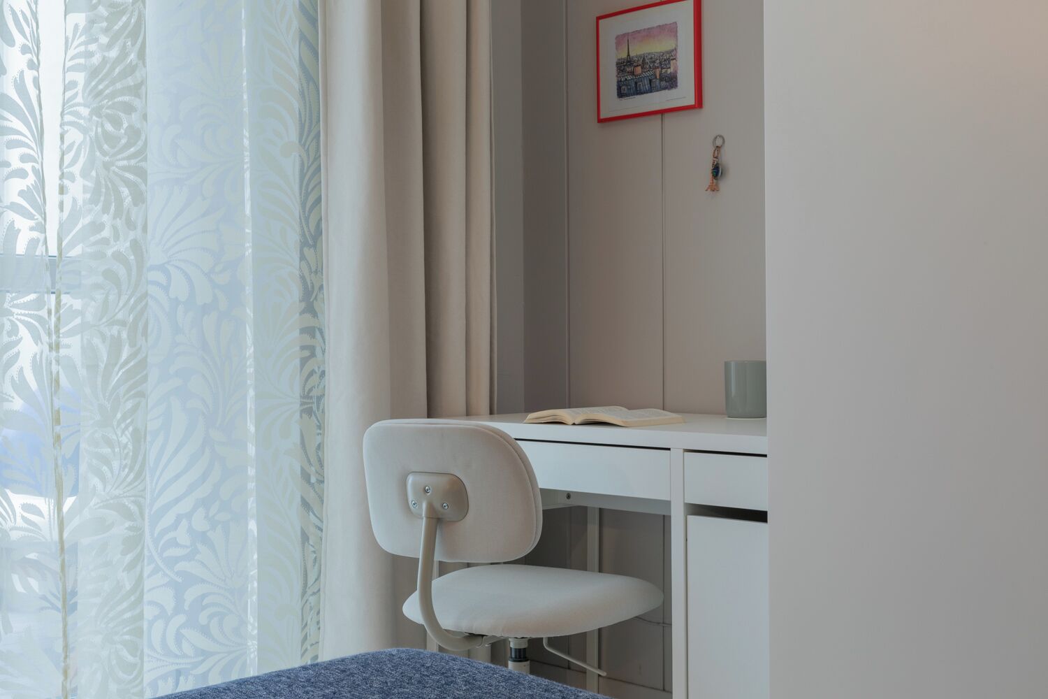 Une chambre à coucher avec un lit, un bureau avec une chaise, une fenêtre avec des rideaux et un tableau au mur.
